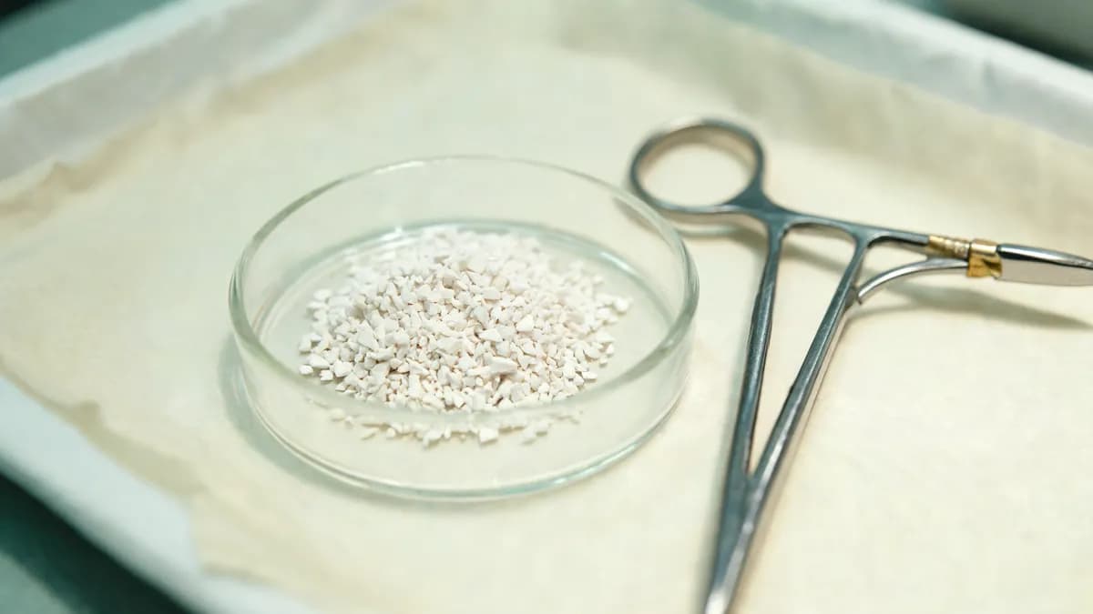 Close-up of sterile bone graft granules in a small glass dish on a surgical tray